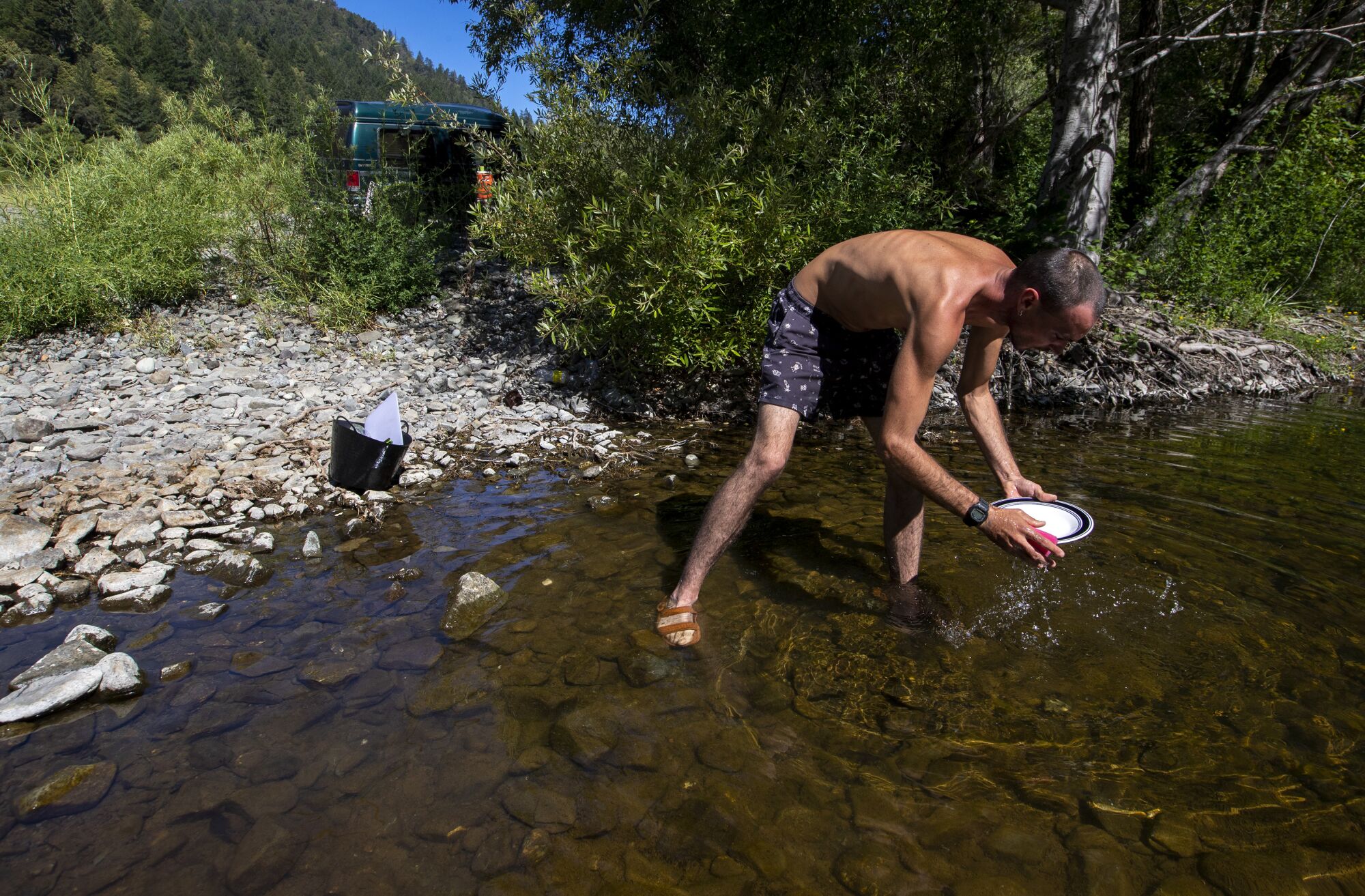 Cristiano washes dishes in the Eel River.
